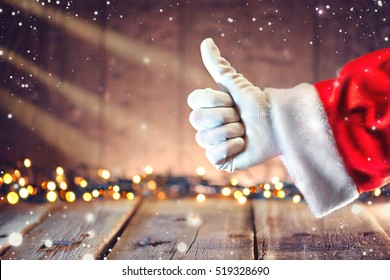 Santa Claus hand Thumb up gesture over Christmas holiday wooden rural background. Beautiful Empty Christmas room. New Year Background. Thumbup