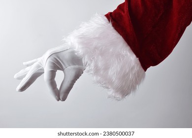 Santa claus hand with white glove and red traditional costume making gesture of catching something delicately with white gradient background. - Powered by Shutterstock