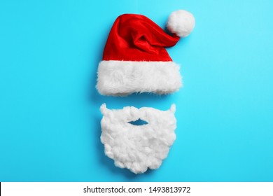 Santa Claus Hat And Beard On Light Blue Background, Flat Lay