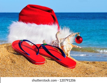 Santa Claus hat and slippers on the seashore against blue sky - Shutterstock ID 120791206