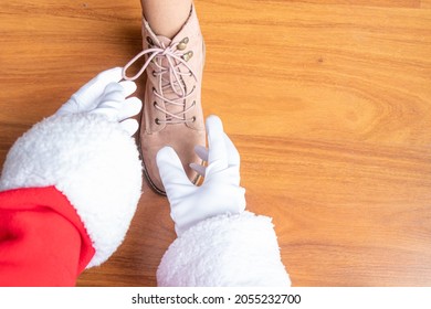 Santa Claus Is Helping A Little Girl Tie Her Pink Shoelaces