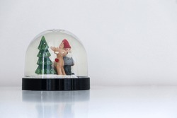 Santa Claus, His Reindeer And A Christmas Tree Inside Christmas Snow Globe, Staring Out At White Snowy Background And Copy Space On The Right