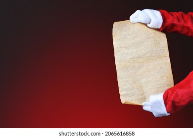 Santa Claus holding a blank scroll - Naughty and Nice List over a red background. Hands and arms only with copy space, . - Powered by Shutterstock