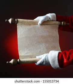 Santa Claus Holding His Naughty And Nice List Over A Light To Dark Red Background. The List Is Blank, Ready For Copy. Only Santa's Hands And Arms Are Visible.