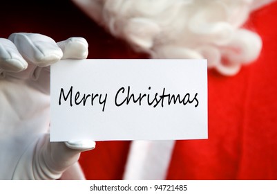 Santa Claus Holding A Merry Christmas Card In A White Gloved Hand