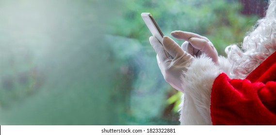 Santa Claus holding mobile phone ready for Christmas time on green background. The season, winter, holiday, celebration, gift concept - Powered by Shutterstock