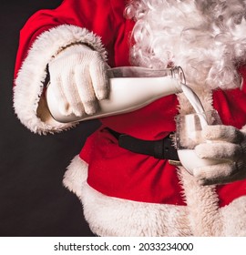 Santa Claus holds a bottle of milk in his hands and pours milk into a glass. Fragment close-up. - Powered by Shutterstock