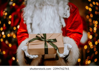 Santa Claus holds a gift in his hands. Close-up Santa's hands holding a gift. - Powered by Shutterstock