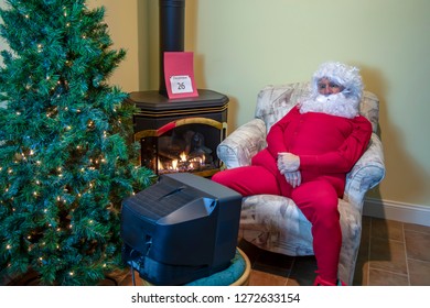 Santa Claus In House Watching Football On TV Wearing Red Long Johns Relaxing The Day After Christmas.