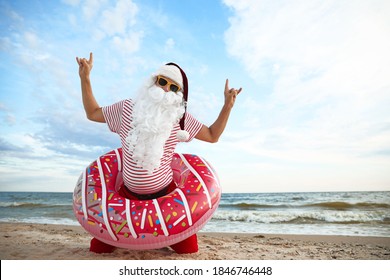 Santa Claus with inflatable ring having fun on beach, space for text. Christmas vacation - Powered by Shutterstock