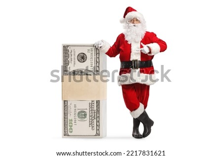 Santa claus leaning on a stack of money and pointing isolated on white background