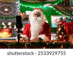 Santa Claus is live streaming a video blog sharing Christmas traditions from his festive North Pole cabin. Saint Nick in his red suit engages with online followers during the holiday season.