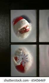 Santa Claus Looks Out Through The Snow And Fog On His Workshop Window In The North Pole To See Outside Check The Weather While He Holds Up A Large Snow Flake  On December 24th, Christmas Eve