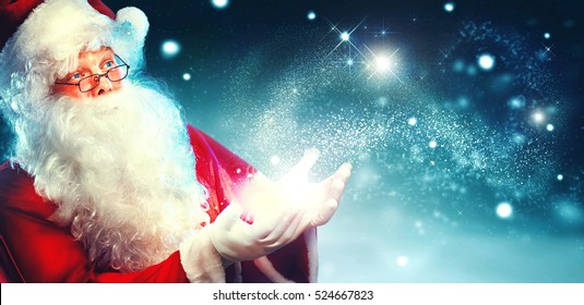 Santa Claus with magic gift in his hands. Portrait of happy Santa Claus making magic at night, Blowing Magic Christmas Stars