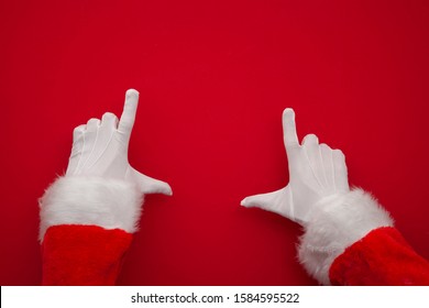 Santa Claus Making Frame With Hand On Red Background With Copy Space