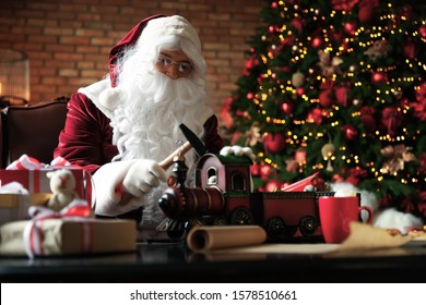 Santa Claus Making New Toy For Christmas In Workshop