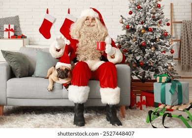 Santa Claus with mug of tea and cute French bulldog in hat at home on Christmas eve - Powered by Shutterstock