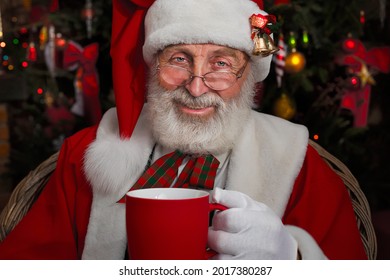 Santa Claus near fireplace and Christmas tree. Festive interior inside Wooden house, New Year's cheerful mood Spirit of Christmas. Senior man with real white beard cosplay Father Christmas. - Powered by Shutterstock