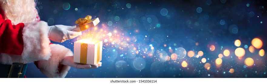 Santa Claus Opening Christmas Present With Golden Stars In Night
