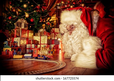 Santa Claus Playing With Toys Under The Christmas Tree.