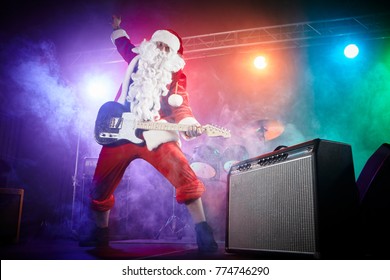 Santa Claus Plays Rock On The Guitar. Stage Light, Smoke.