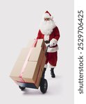 Santa Claus pushing a hand truck and delivering boxes, Christmas and delivery concept