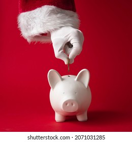 Santa Claus Putting Money Into A Christmas Piggy Bank Money Box. Festive Saving Concept