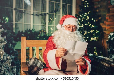 Santa claus read letter from children over living room, christmas tree. Happy santa writing list with a quill at home.Holidays, childhood and people concept  - Powered by Shutterstock