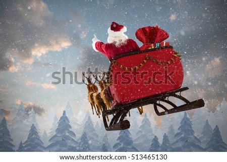 Santa Claus riding on sled with gift box against snow falling on fir tree forest