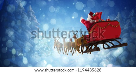Santa Claus riding on sleigh with gift box against winter village