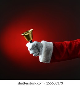 Santa Claus Ringing A Bell With A Red Background. Square Format With Only Santa's Hand And Arm Visible.