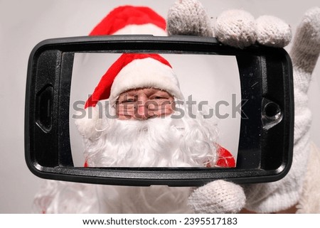 Santa Claus Selfie. Santa Claus taking a selfie with a cell phone. Chris Cringle taking a Selfie Photo with his Cell Phone for Christmas Pictures. Happy Santa Claus doing a Video Chat with his Phone.