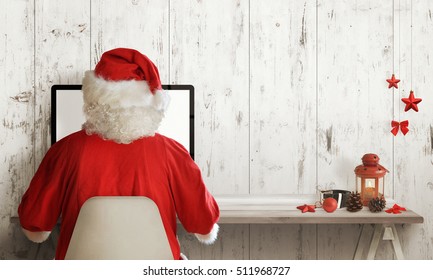 Santa Claus shopping on computer. Christmas sale time. Free space for text. Christmas decorations beside.