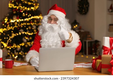 Santa Claus showing thumb up while signing Christmas letters at home - Powered by Shutterstock