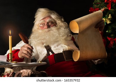 Santa Claus sitting at home and writing on old paper roll to do list with quill pen and ink at night with candle light. Authentic vintage style portrait. - Powered by Shutterstock