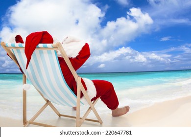 Santa Claus Sitting On Beach Chairs With Blue Sky And Cloud.Christmas Day Concept.