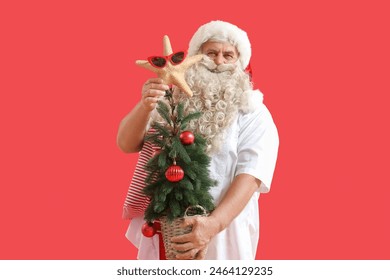 Santa Claus with starfish and fir tree on red background. Christmas in July - Powered by Shutterstock