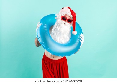 santa claus in suit with inflatable swim ring in sunglasses rests on the beach on blue isolated background, santa tourist goes on vacation at sea - Powered by Shutterstock