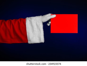 Santa Claus Theme: Santa's Hand Holding A Red Card On A Dark Blue Background