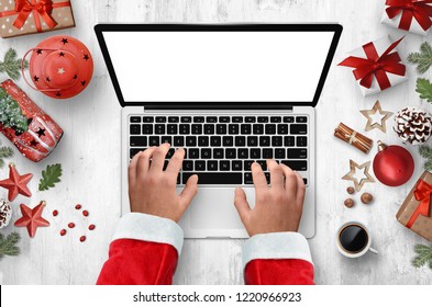 Santa Claus use laptop with empty screen on white desk with Christmas decorations. Empty space for text, advert. Mockup - Powered by Shutterstock