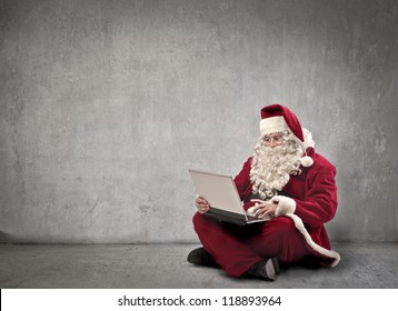 Santa Claus Using A Laptop Computer In A White Dark Room