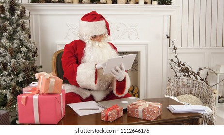 Santa Claus using tablet to give a quick video call to the North Pole - Powered by Shutterstock