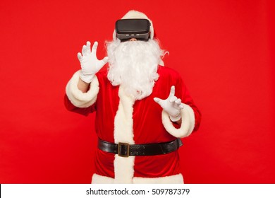 Santa Claus wearing virtual reality goggles, on a red background. Christmas - Powered by Shutterstock