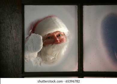 Santa Claus Wipes The Snow And Fog Away From His Workshop Window In The North Pole To See Outside And Make Sure His Raindeer Are Getting Ready To Go To Work On December 24th, Christmas Eve