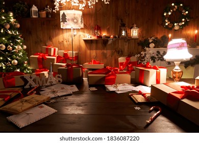 Santa Claus workshop home wooden decorated table with Merry Christmas tree, decor, wrapped gifts presents boxes on holiday eve in cozy home interior late in night with lamp light on xmas background.