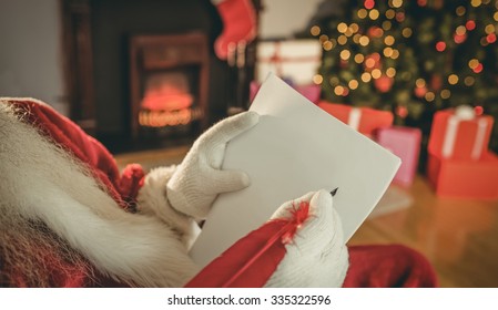Santa claus writing list with a quill at home in the living room ภาพถ่ายสต็อก