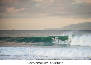 Santa Cruz Island in background as surfer flies across wind blown wave face.