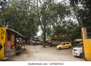 Santa Fe De Antioquia, Colombia - Nov 8th 2018: Local Colombians Board Buses And Small Yellow Taxi Cabs In The Bus Depot Of Small Town Santa Fe