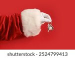 Santa hand with key and house shape keychain on red background, closeup