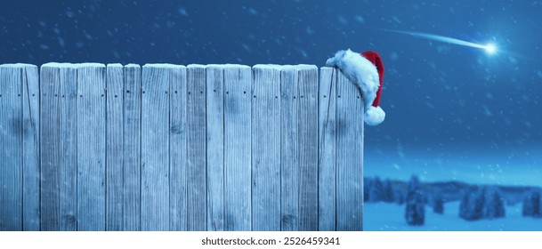 Santa hat on a rustic wooden fence and shooting star in the sky, Christmas background - Powered by Shutterstock